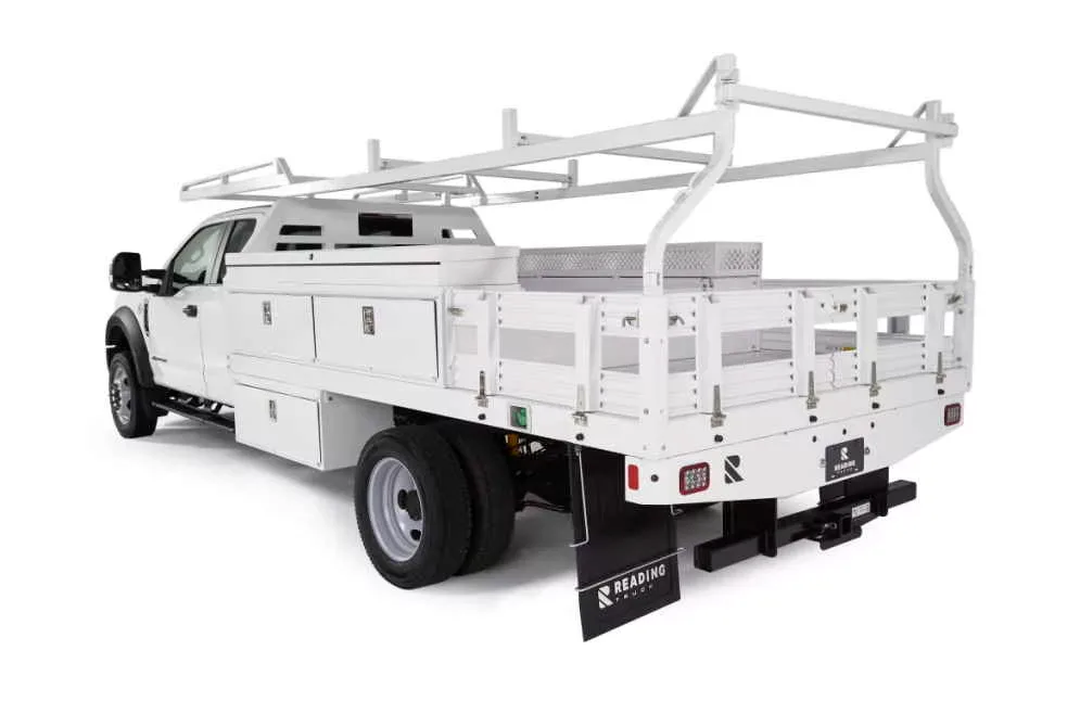 A white contractor flatbed truck fitted with a ladder rack