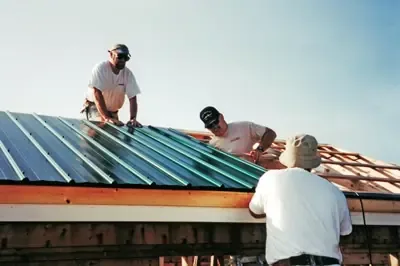Three roofers installing a metal roof