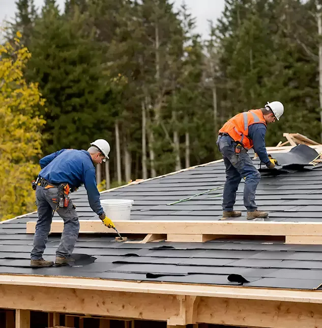 A roofer mounting rails on a shingle roof under a blue sky