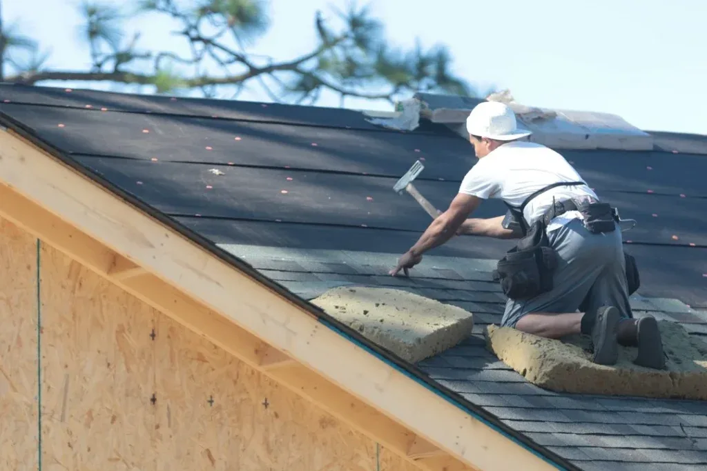 Two roofers drilling grey tile at sunset